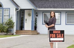 Real estate sales woman in front of house for sale
